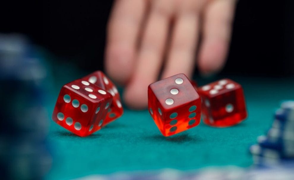A hand rolling dice on a green casino table.