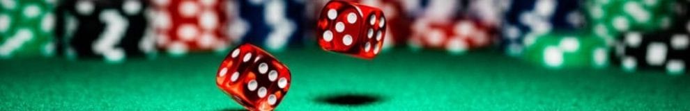 Two dice rolling on a casino table surrounded by casino chips.