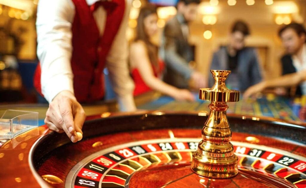 A casino croupier adding a ball to the roulette wheel.