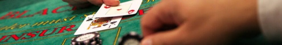 A dealer puts two cards down on a blackjack table.