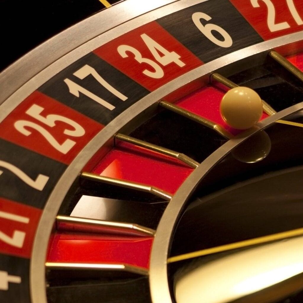 A close-up of a roulette wheel with a white ball in a red pocket.