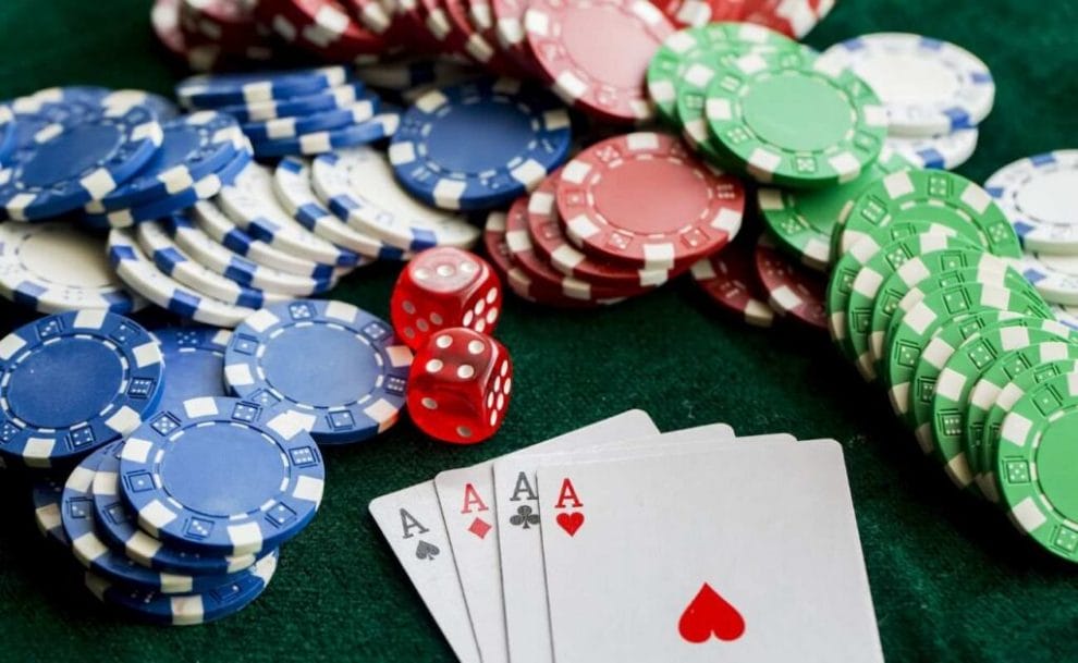 four of a kind ace playing cards, poker chips and red six sided dice on a table 