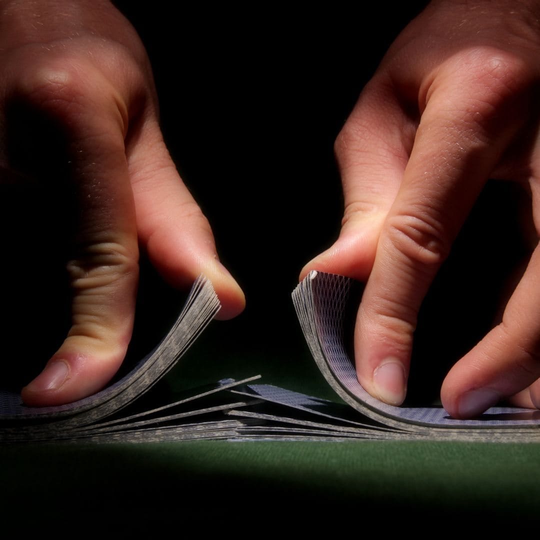 A close up of a person shuffling cards at a poker table.