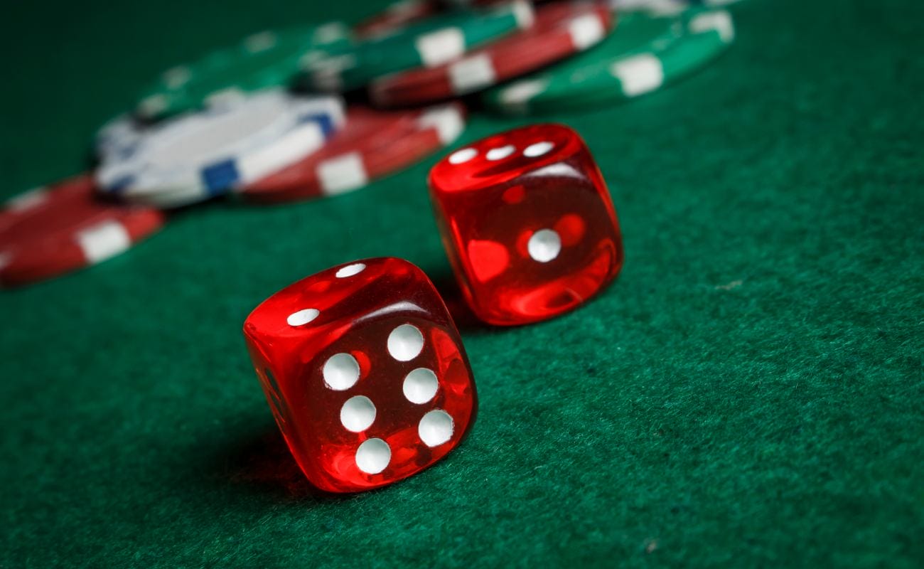 Red dice and casino chips on a green felt table.