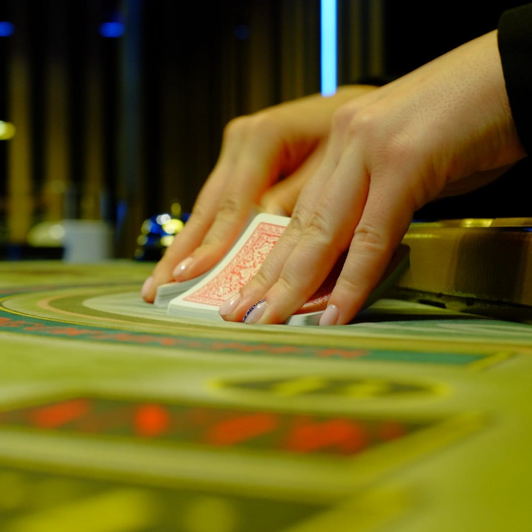 Hands getting ready to shuffle cards on a poker table.