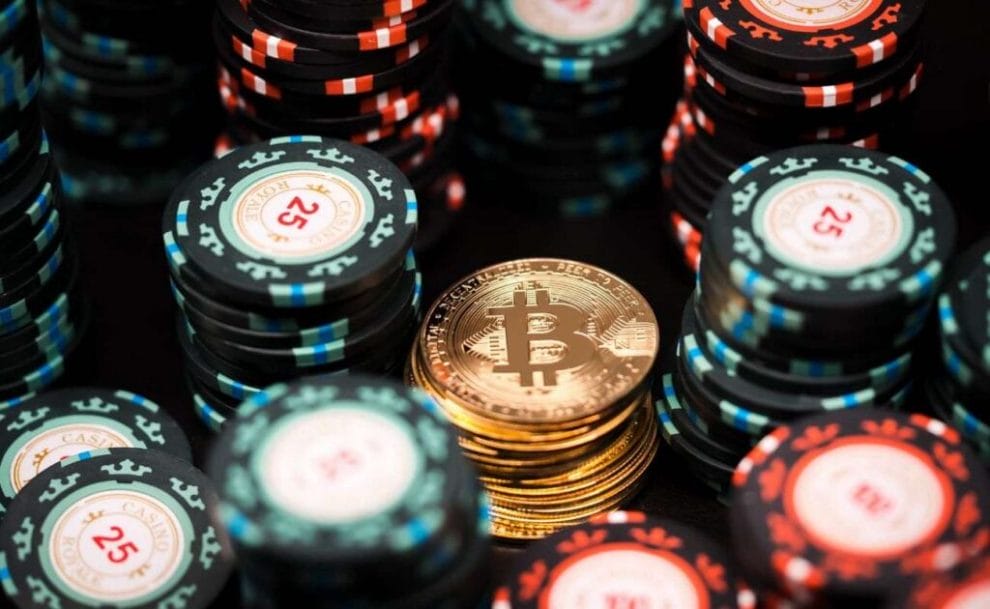 A closeup of a stack of gold Bitcoins surrounded by stacks of poker chips.
