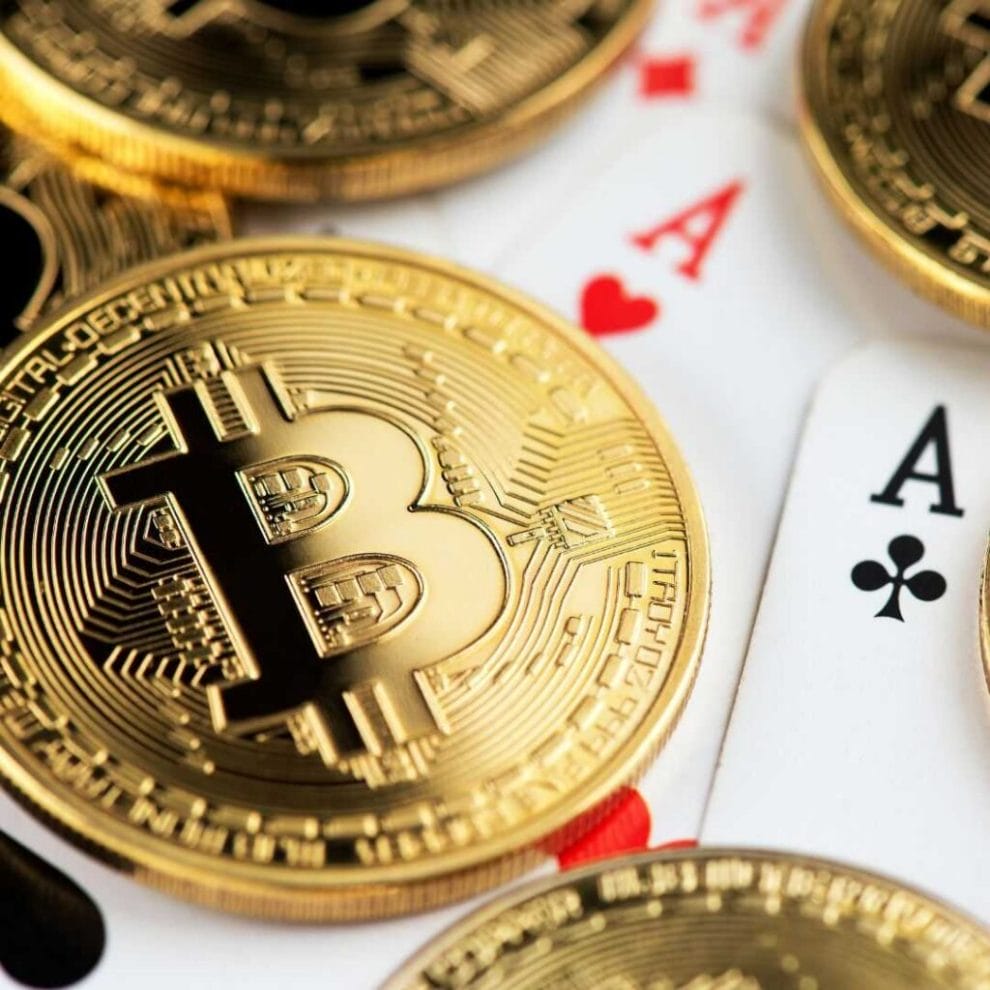 A closeup of six gold Bitcoins on top of two Ace playing cards.