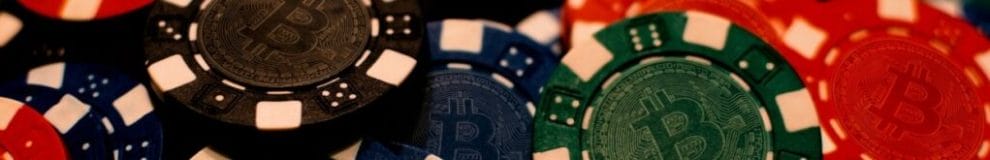 Casino chips of various colors with the Bitcoin logo on them.