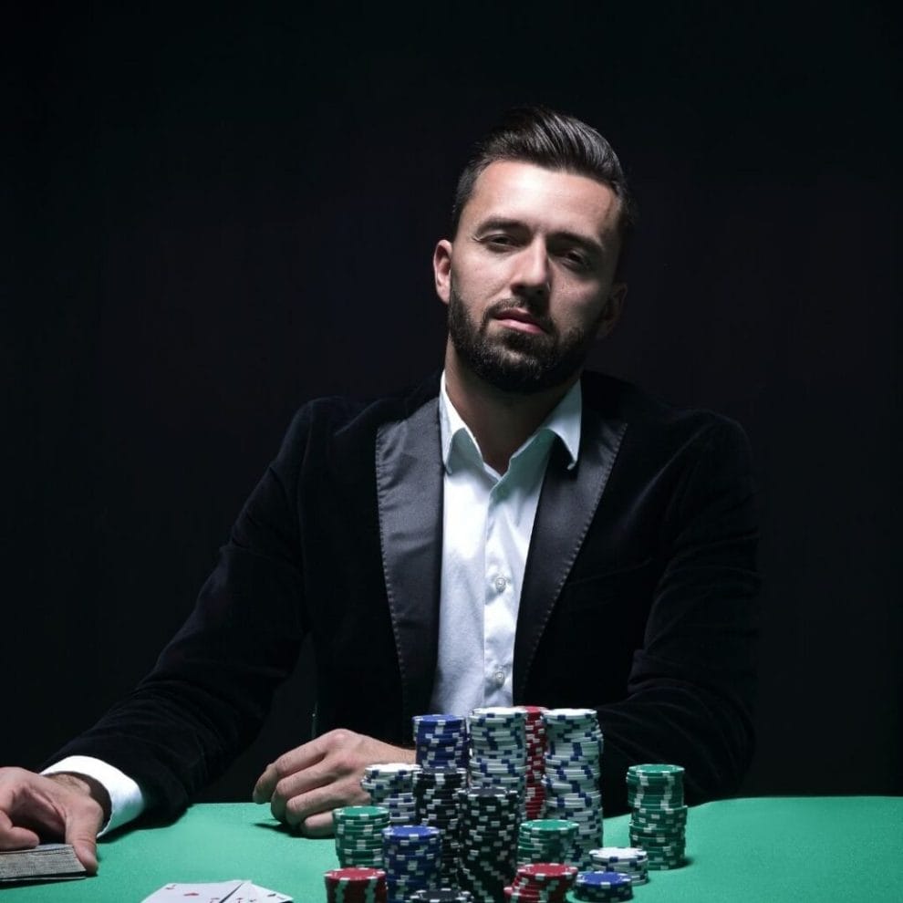 a man sitting at a green felt poker table with stacks of poker chips in front of him