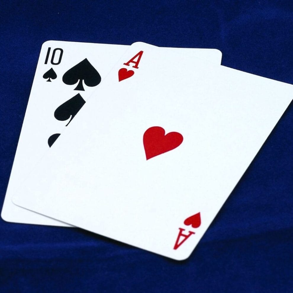 Ace of Hearts and Ten of Spades playing cards on a blue surface background