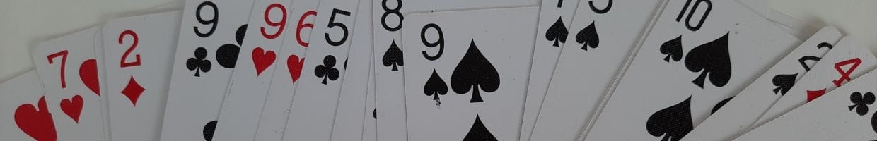 an unordered, messy spread of playing cards spread out on a surface