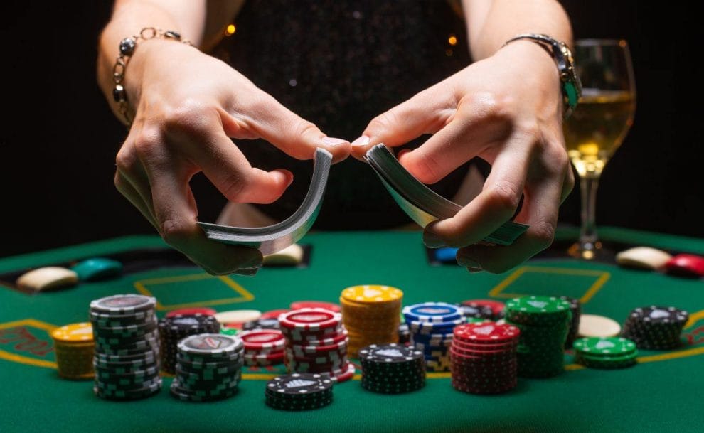 A dealer shuffling cards at a poker table, with casino chips arranged on the table. 