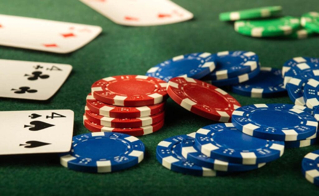 Casino chips and playing cards on a green felt table.