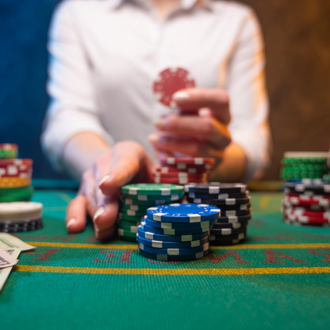 Woman pushing casino chips on a poker table.