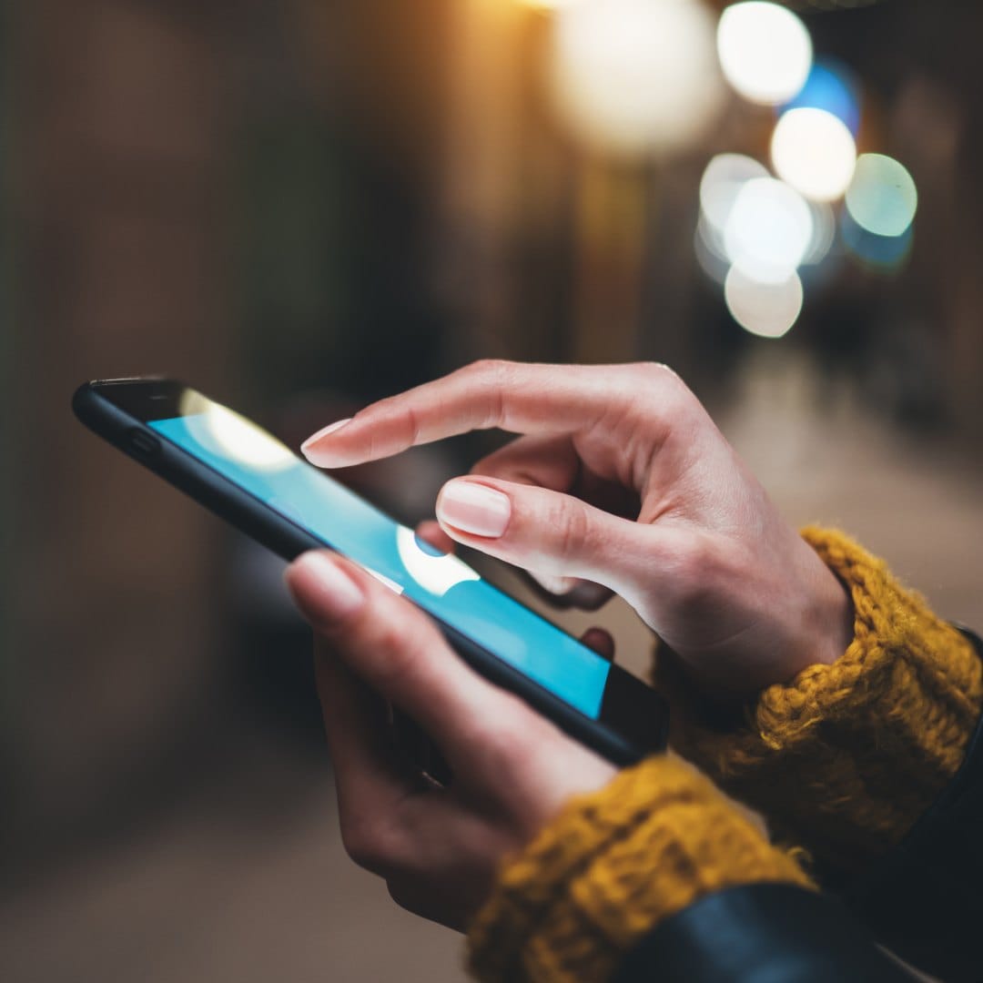 Hands using a smartphone with a blue screen.