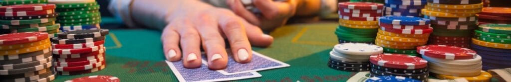 A hand touching playing cards with poker chips on the table.