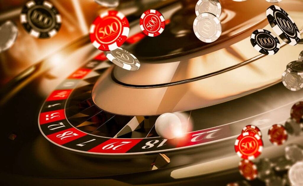 An extreme closup of a gold roulette wheel with red and black casino chips floating around it.