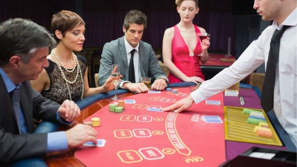  A group of people, and a poker dealer, sitting around a poker table, playing a game of poker. 