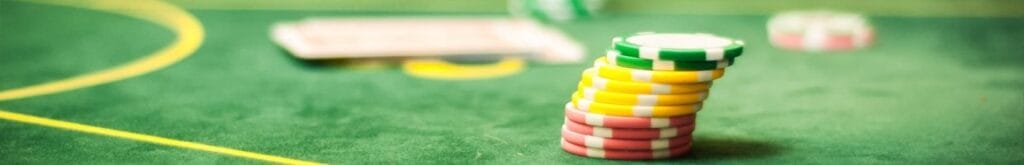 A close up of a stack of red, yellow, and green poker chips on a poker table.