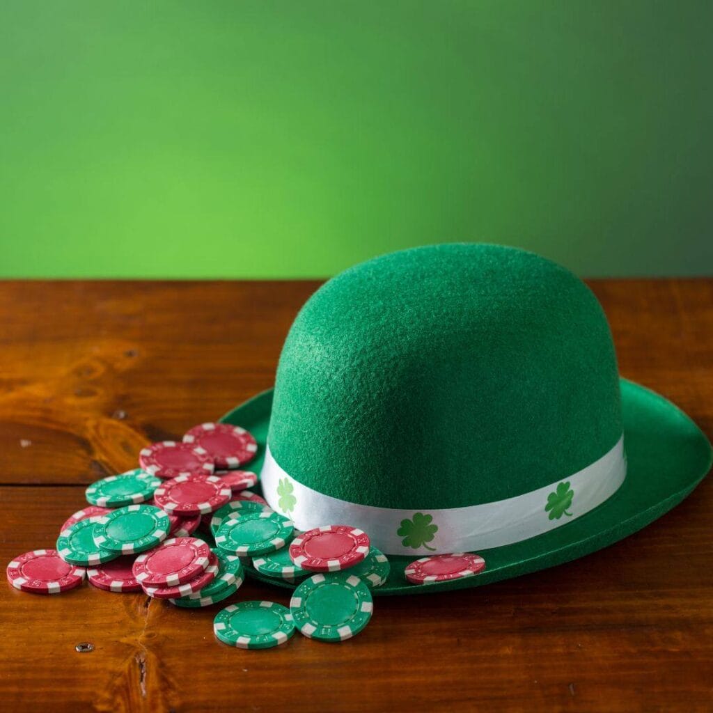 A green Irish themed hat, and red and green casino chips arranged on a table.