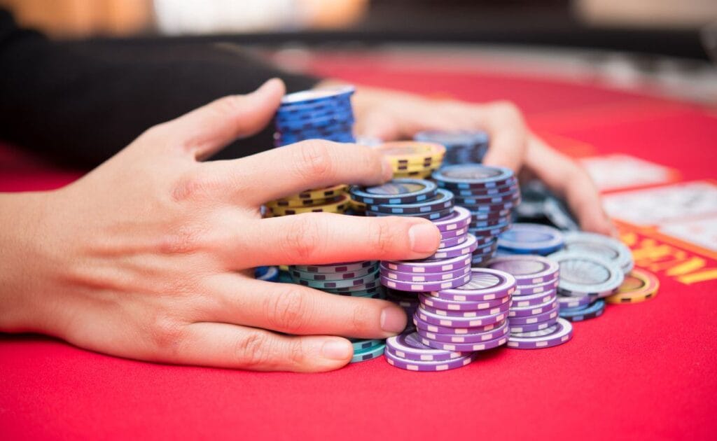 A person clutching a hefty stack of casino chips on a poker table.