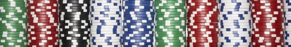 Stacks of green, red, black, white, and blue poker chips lined up next to each other. 