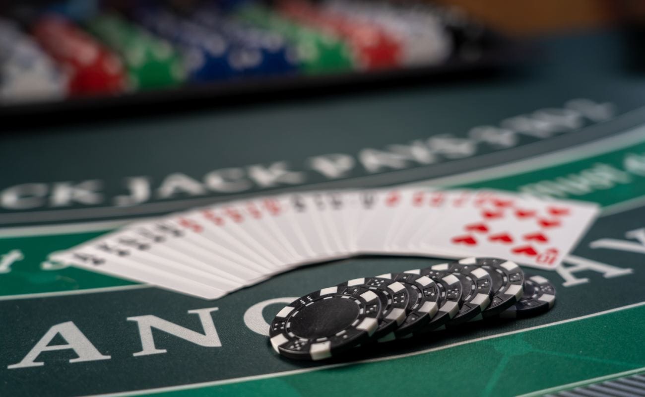 Blackjack cards and black casino chips on a green felt table.
