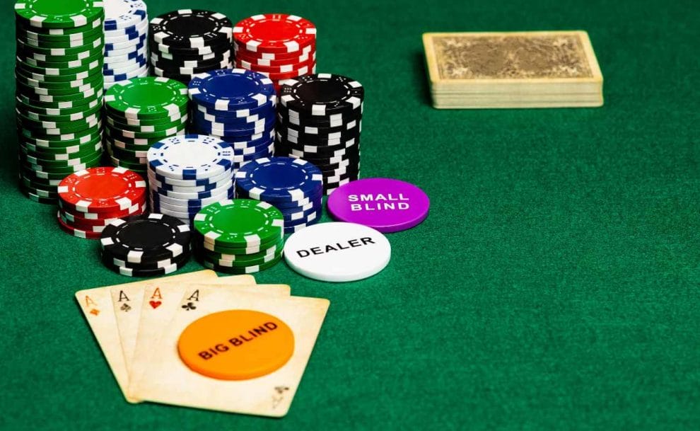 Special chips labeled 'Small Blind', ‘Dealer’, and  'Big Blind' placed on the poker table alongside regular poker chips, and playing cards. 