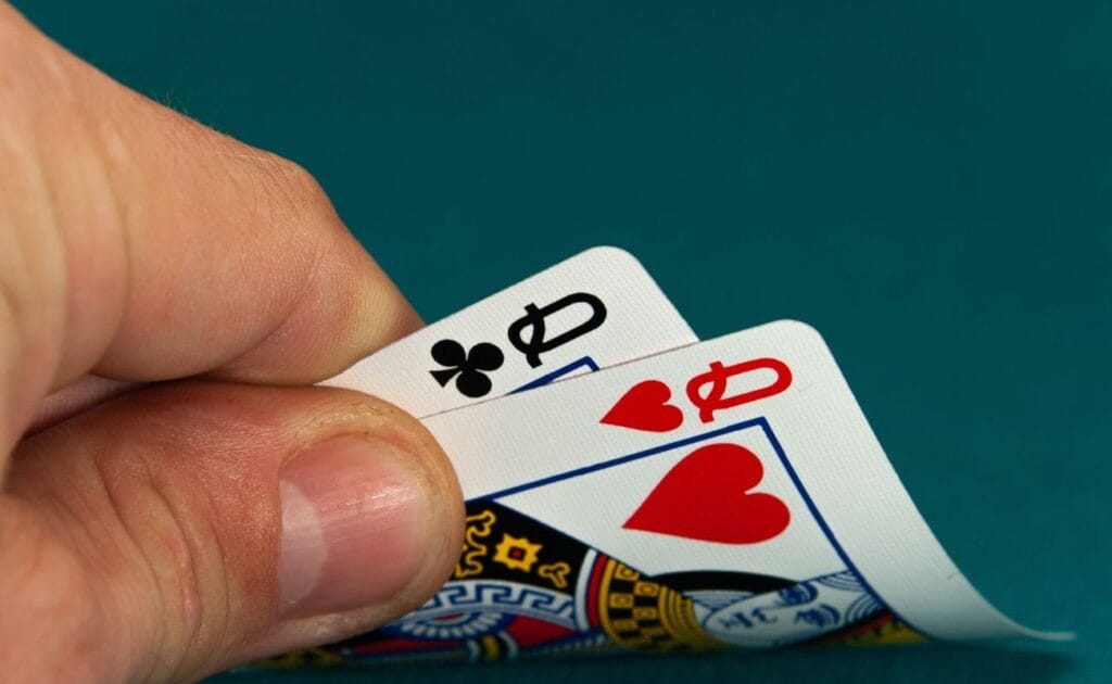 a person checking their hole cards of a pocket pair of queens