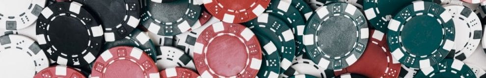 A close up of red, black, green, and white poker chips. 