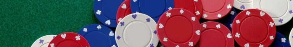 Red, white, and blue poker chips on a green felt table.