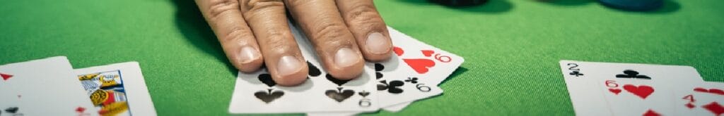 A poker player with his hands on three cards of nine