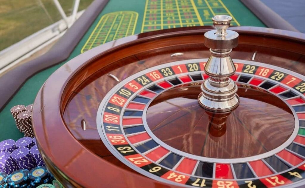 A roulette wheel and casino chips, by a roulette table, in a casino