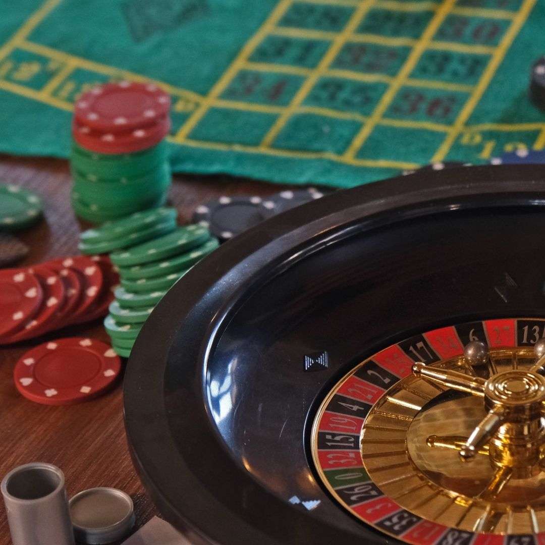 A closeup of a roulette wheel, and casino chips on a table.