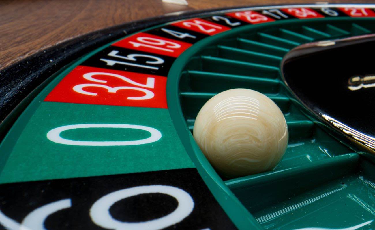 Closeup of a roulette ball in the “0” slot on the wheel.