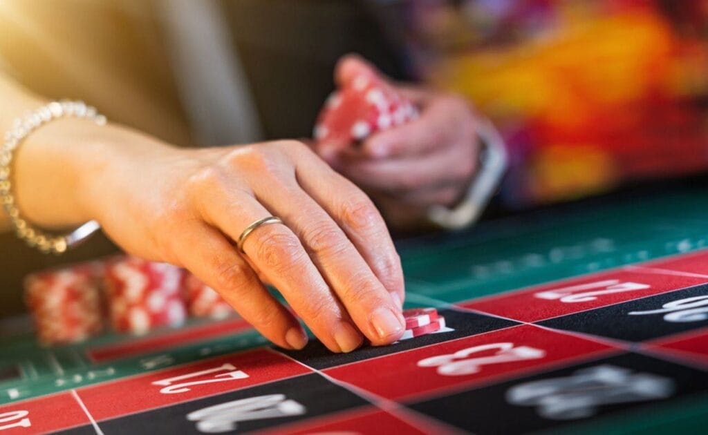 A woman placing a chip on a number at a roulette table.