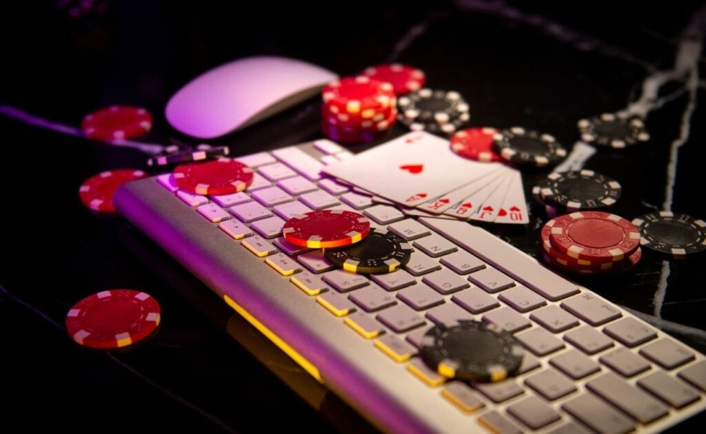 Playing cards and poker chips sit atop and beside a keyboard