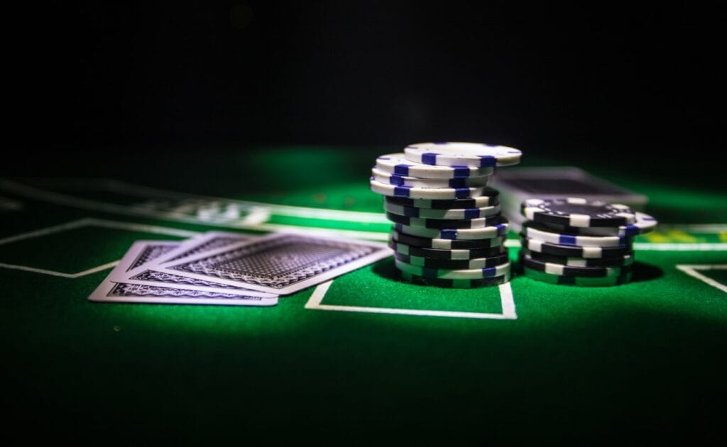 Blackjack cards and casino chips on a green felt table.