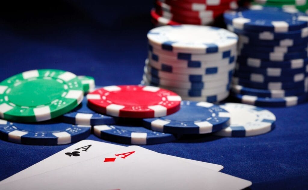 Casino chips and playing cards on a blue felt table.