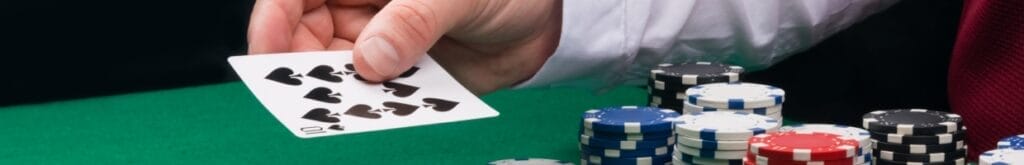 A dealer passes a playing card on a blackjack table with casino chips.