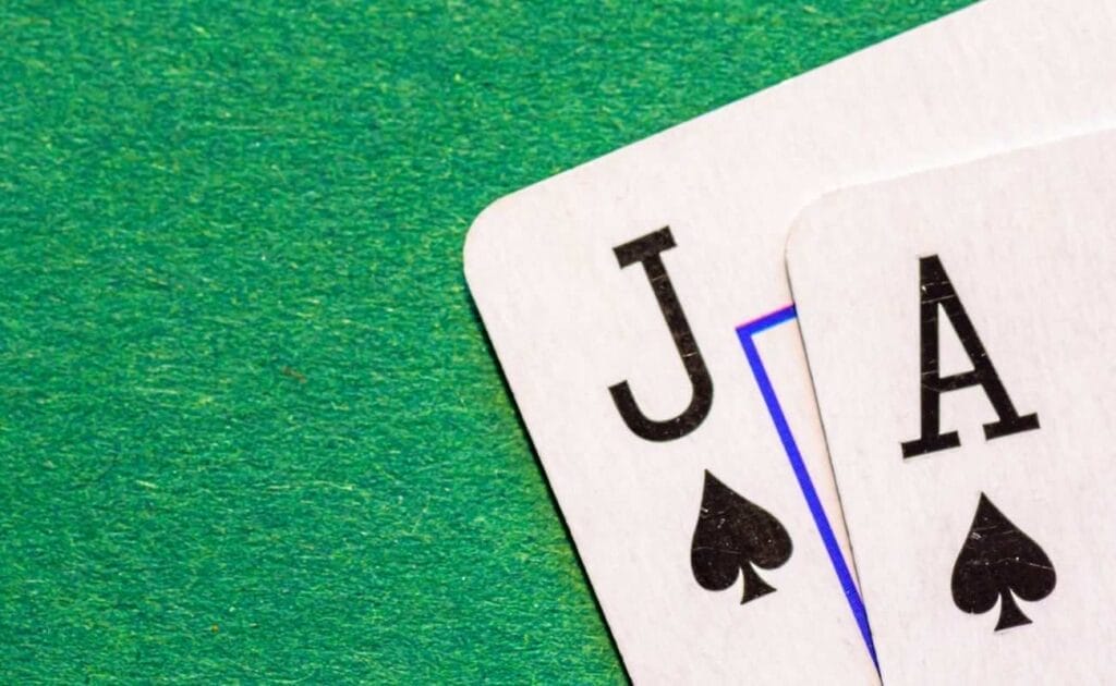 close up of an ace and jack of spades playing cards on a green felt poker table
