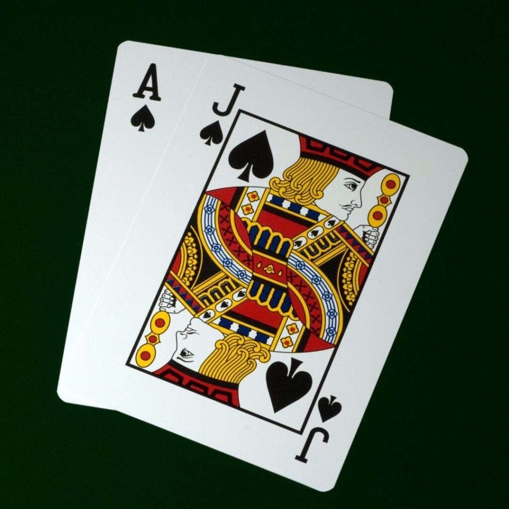 an ace and jack of spades playing cards with a dark green background