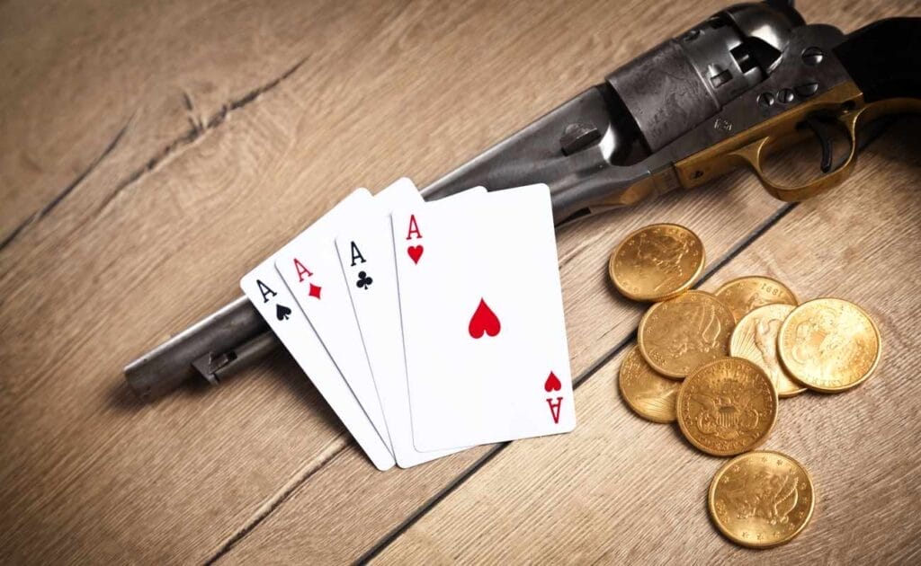 Four aces lay on top of a pistol with gold coins beside them