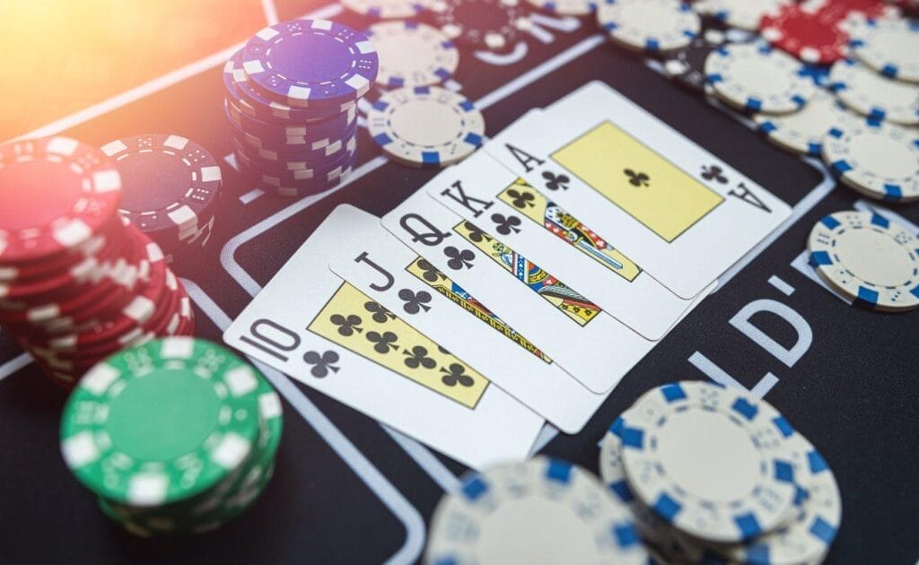 A royal flush on a poker table. It’s surrounded by stacks of poker chips.