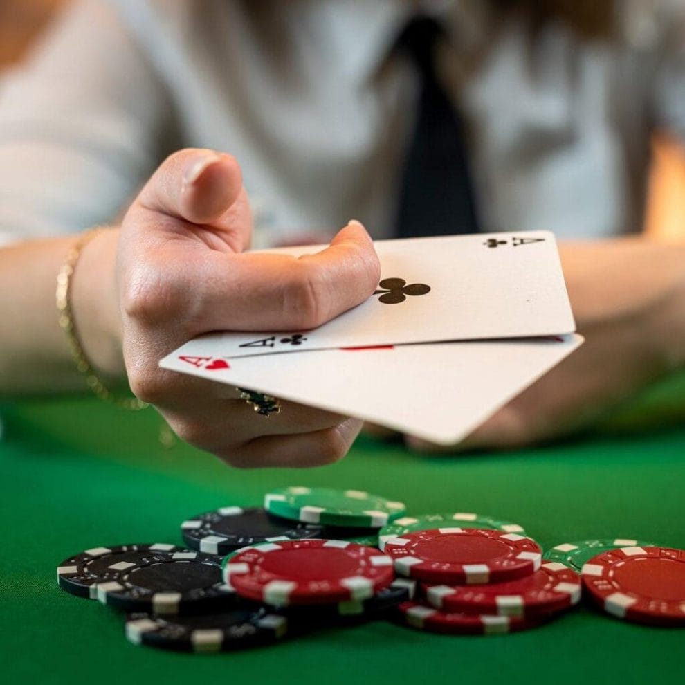A poker player holding two aces between their fingers.