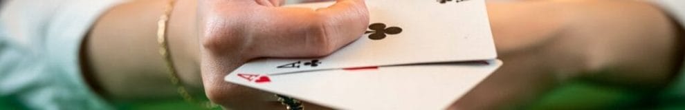 A poker player holding two aces between their fingers.