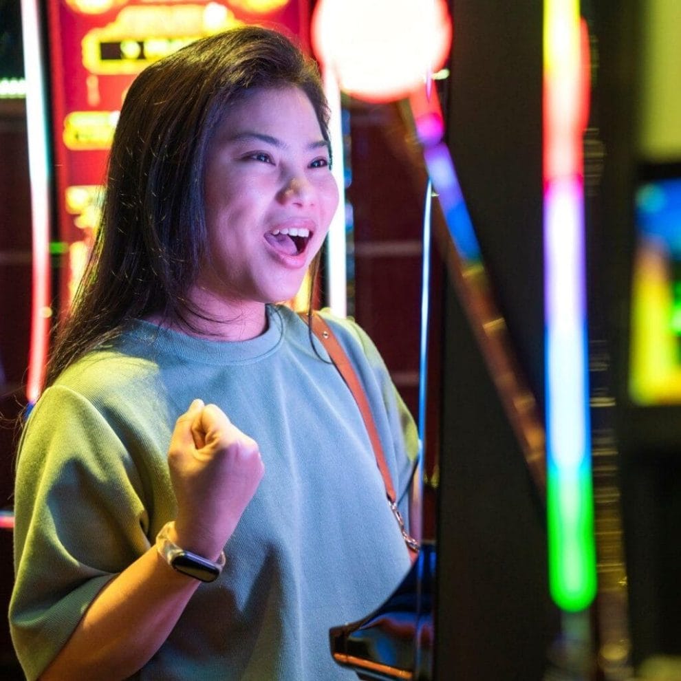 A smiling person playing slots in a casino.