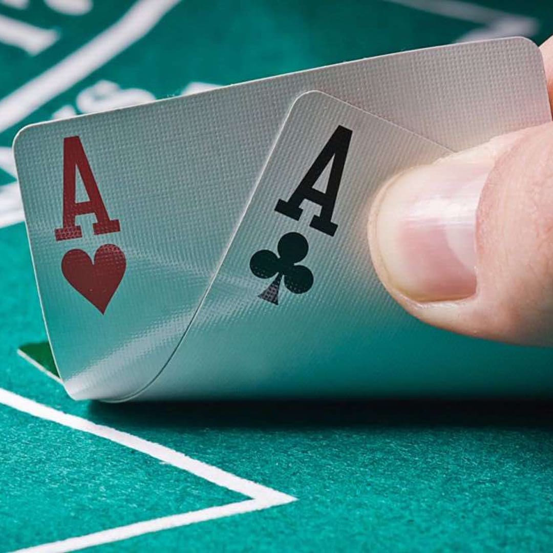 A man holding to ace playing cards at a poker table.