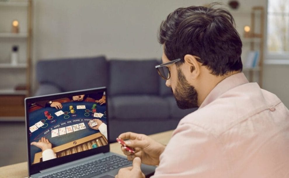 A man looking at a laptop screen as he plays a game of online poker.