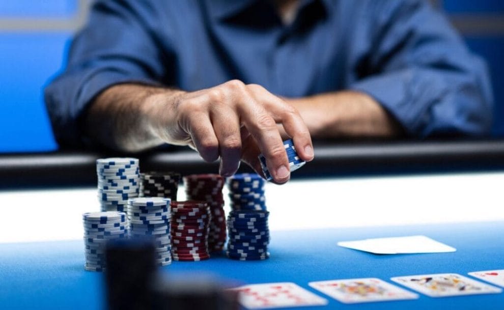 A man at a poker table picking up a large stack of chips as he makes his next move.